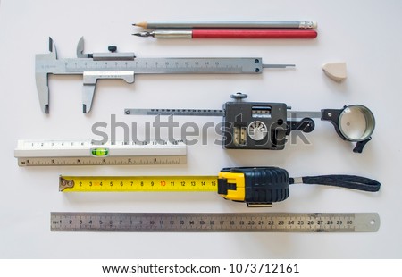 Measuring instruments and tools insulated on a white sheet. Set with various rulers, planimeter, caliper, pencil, ink pen for use in manufacturing process industrial sector.