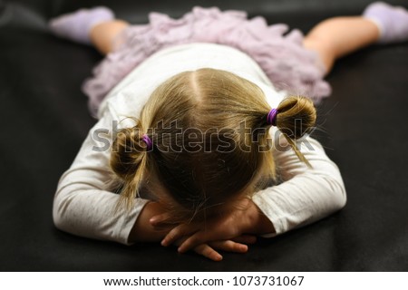 Child girl upset lying on the floor and crying on a black background Royalty-Free Stock Photo #1073731067