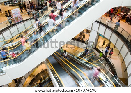 People in motion in escalators at the modern shopping mall. Royalty-Free Stock Photo #107374190