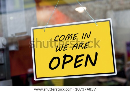 come in we are open sign hanging on a window door outside a restaurant, store, office or other Royalty-Free Stock Photo #107374859