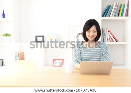 a young asian woman using laptop in the dining room Royalty-Free Stock Photo #107375438