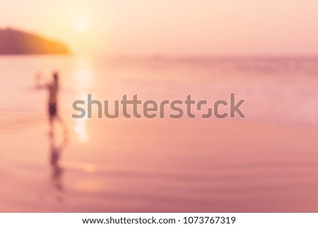 Blur woman take picture and relax on tropical sunset beach with bokeh sun light wave abstract background. Copy space of summer vacation and business travel concept. Vintage tone filter color style.