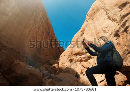 Female photographer takes picture  with rock formation in the Arches National Park, Utah, USA.