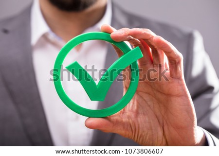 Close-up Of A Businessperson's Hand Holding Green Check Mark Icon