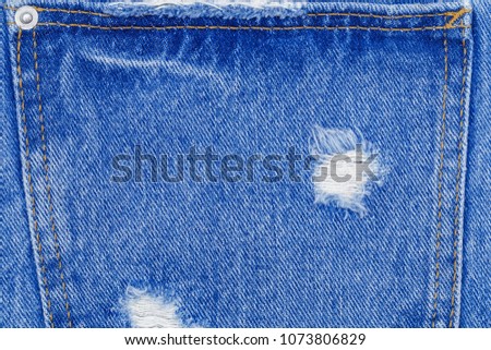 Hole on blue Denim Jeans. Ripped Destroyed Torn Blue denim pocket background. Close up blue denim  fabric texture.
