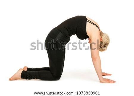Side full body view of a young woman in front of white background the Yoga exercise showing the cat (Marjaryasana).