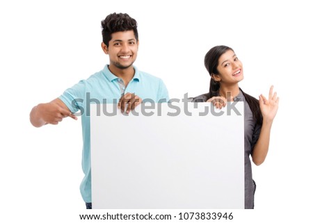Cheerful cute young couples holding and pointing white board on white.