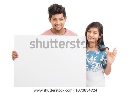 Cheerful cute young couples holding and pointing white board on white.