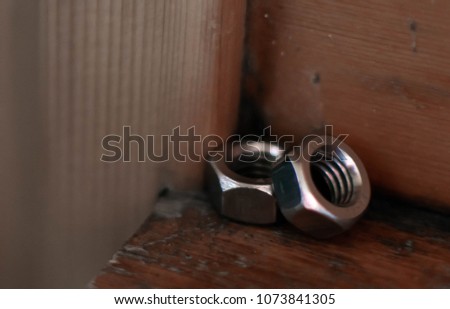 Mechanical nuts of shiny metal on industrial brown wooden background
