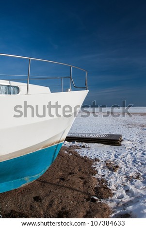 Winter frozen boat on the snow sea coast