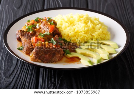 Ecuadorian traditional food: seco de chivo goat meat with a garnish of yellow rice and avocado close-up on a plate on the table. horizontal
 Royalty-Free Stock Photo #1073855987