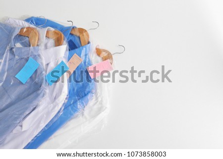 Clean clothes after dry-cleaning on white background Royalty-Free Stock Photo #1073858003