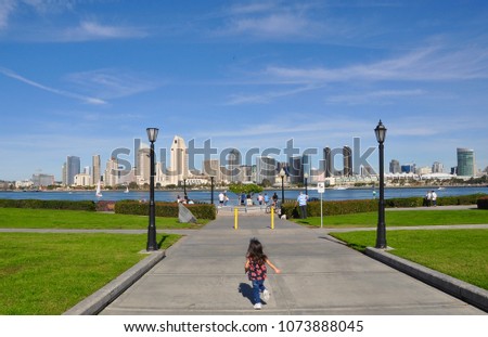 Little girl running away with the view of San Diego skyline in backdrop