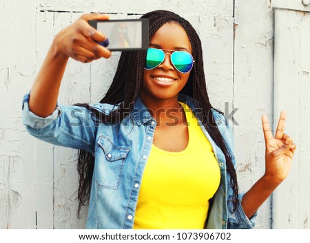 Cool girl taking self-portrait photo on a smartphone in the city