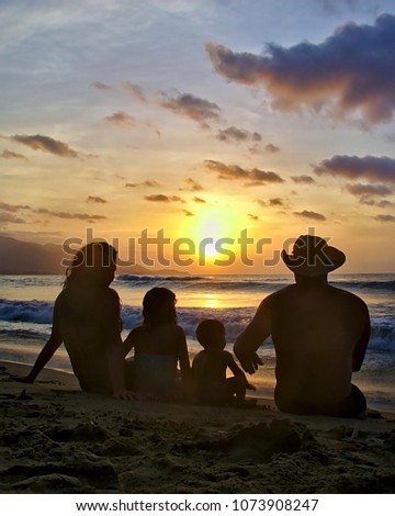 family enjoys a sunset from a caribbean beach