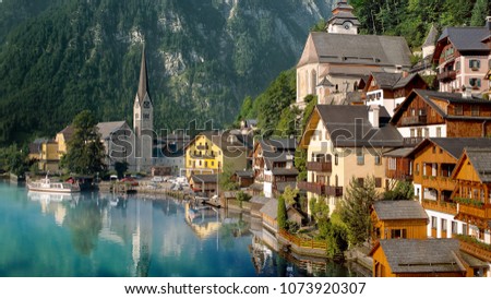 Scenic picture-postcard view of famous Hallstatt lakeside town reflecting in Hallstattersee lake in the Austrian Alps in beautiful morning light on a sunny day in summer, Salzkammergut region, Austria