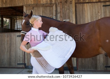 Young Woman Preparing for Horse Riding Royalty-Free Stock Photo #1073926427