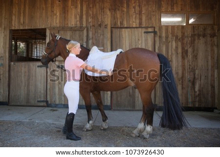 Young Woman Preparing for Horse Riding Royalty-Free Stock Photo #1073926430