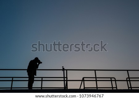 Silhouette of professional photographer taking photo of beautiful sunset