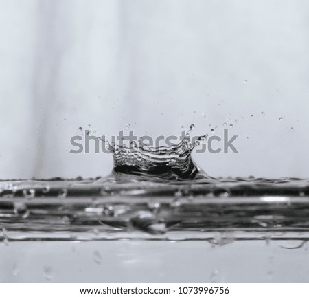 Water drop or rain drop falling on water surface and creating beautiful spread out splash shape 