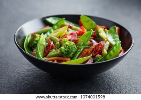 stir fry vegetables in black bowl, dark background, selective focus