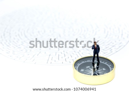Miniature people: Businessman standing on start point of maze with compass , businessman making the right choice concept.