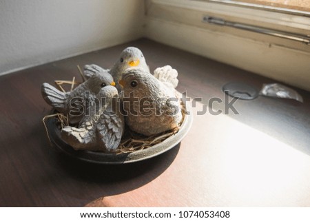 bird statue on a wooden table with sunshine through a window in a morning