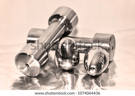 Metal dumbbells and steel eggs, the concept of sports training and the achievement of muscle strength.