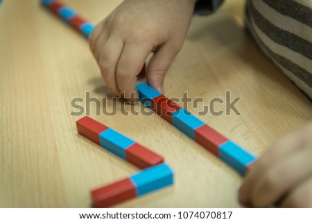 Clouse up picture of curly cute toddler playing with wooden toy.