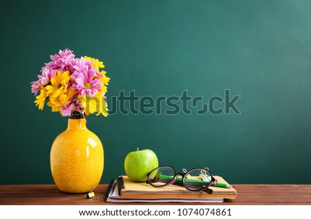 Bouquet of flowers and notebooks with eyeglasses on table. Teacher day celebration
