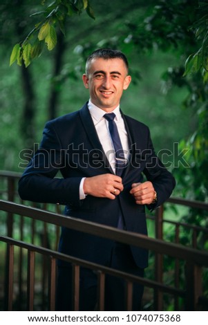 The groom in wedding day in a dark suit, sunny day
