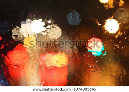 Abstract background with blurred car lights in the rain, colorful bokeh in the night.