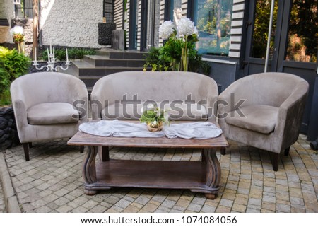 Outdoor composition from vintage sofa and armchair with table in front of it with vase with white eustoma on it