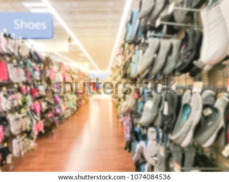 Blurred variety of casual shoes and sandals hanging on display at local retailer store in Texas, USA. Footwear department in modern supermarket row of sneaker, flip flop, sandal for man, women