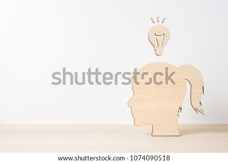 Business and design concept - wooden girl silhouette head with idea lightbulb on wooden desktop and white background 