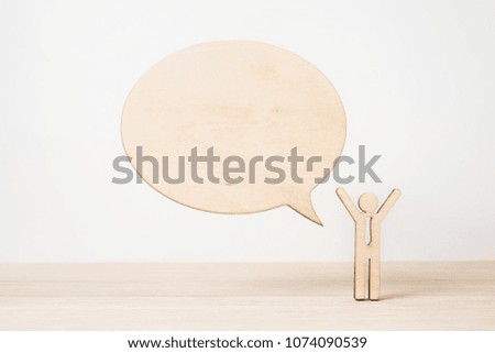 Business and design concept - wooden businessman icon with dialogue frame on wooden desktop and white background 
