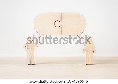 Business and design concept - group of wooden businessman icon with jigsaw dialogue frame on wooden desktop and white background.  it's discussion, leadership concept Royalty-Free Stock Photo #1074090545