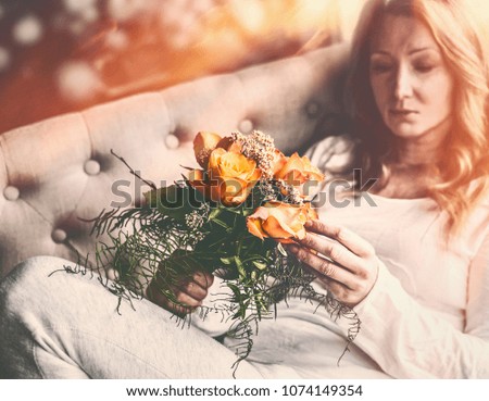 Woman on sofa with Roses bunch in hand  