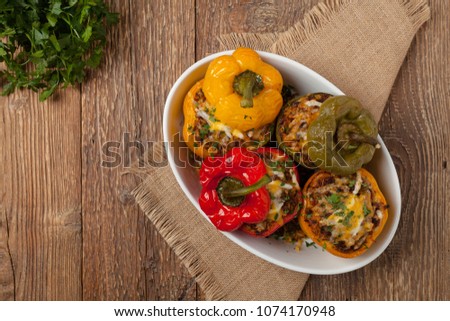 Colorful baked with cheese, stuffed peppers with rice and minced meat. Top view. Natural wooden background. Royalty-Free Stock Photo #1074170948