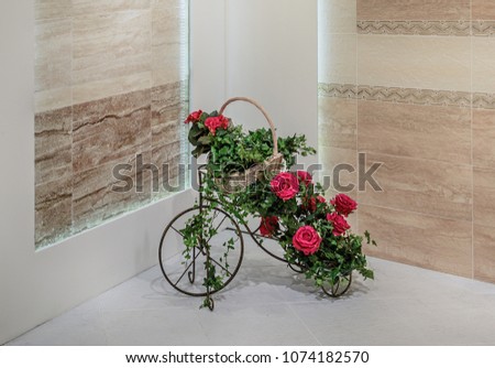 Decorative stand for flowers in the shape of a bicycle is decorated with a basket with flowers, roses, ivy, and bindweed. 