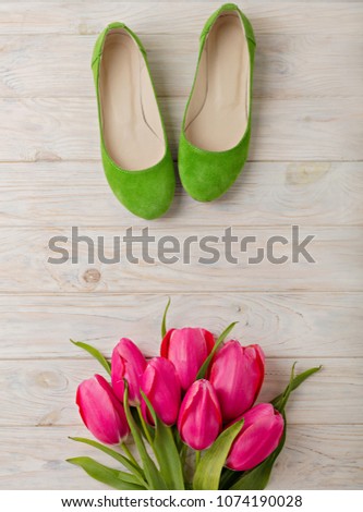 Women's shoes and bouquet of pink tulips on a wooden background. Selective focus.