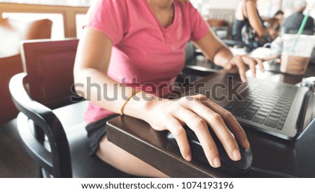 Close up young freelance woman hand working with laptop, cup of coffee on table, typing while sitting at cafe. Female blogger wear casual dress writing content online website with notebook computer.