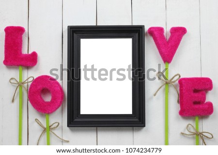 Picture frames and red letters of love are placed on a white wooden floor.