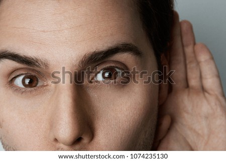 Closeup portrait of Handsome young man trying to listen to the conversation of someone