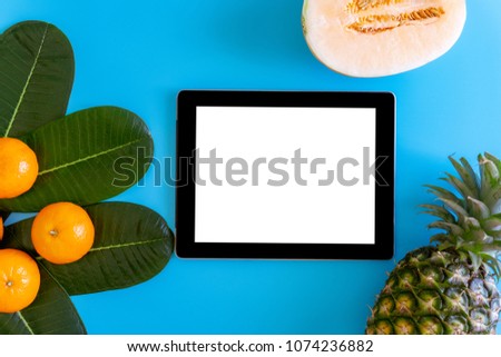 Topview of orange,pineapple, cantaloupe with desktop with blank white tablet on plates blue background. topview or flat lay fruit.
