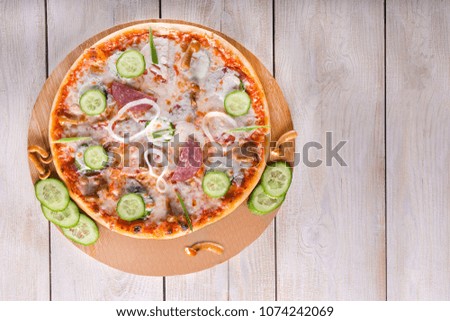 Vegetarian pizza served with fresh tomatoes, cucumbers on wooden background