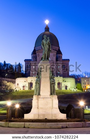 Vertical photo of the statue of St. Andre in front of Canada’s largest church and world-renowned pilgrimage site St. Joseph’s Oratory of Mount Royal at sunrise, Montreal, Quebec, Canada
