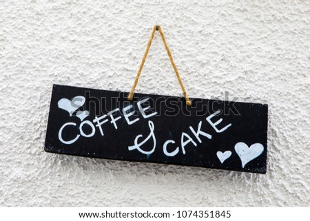 A coffee and cake sign hanging on a wall.