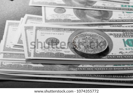 Physical version of Bitcoin (new virtual money) and banknotes of one hundred dollar. Exchange bitcoin for a dollar. Conceptual image for worldwide cryptocurrency and digital payment system. 