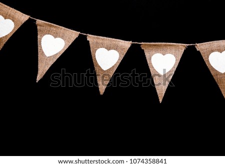 Vintage look fabric pennant flags with white hearts isolated on black. Top border, space for text.